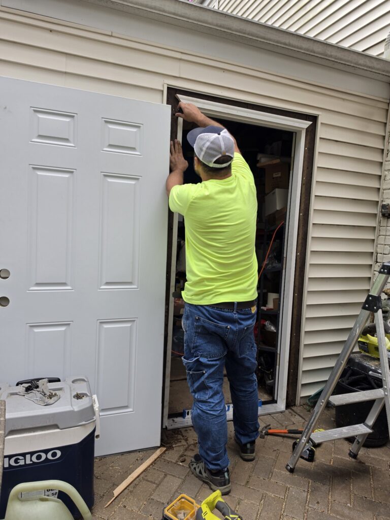 Door installation Chicago — worker fitting a new white exterior door and frame